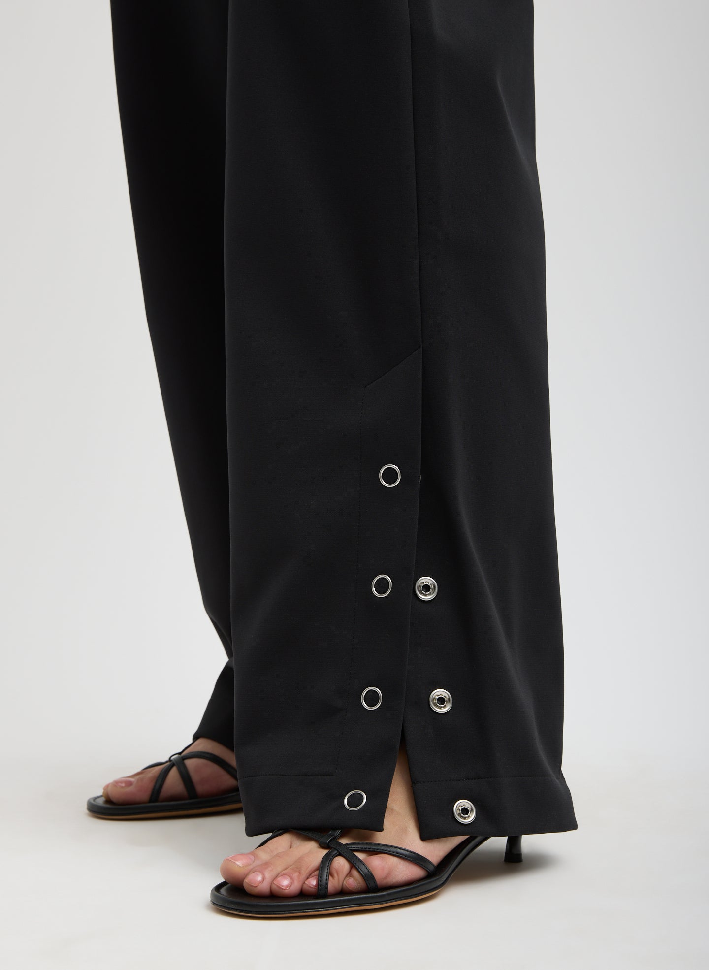 Black Compact Tech Knit Overalls - closeup of snap details at hem