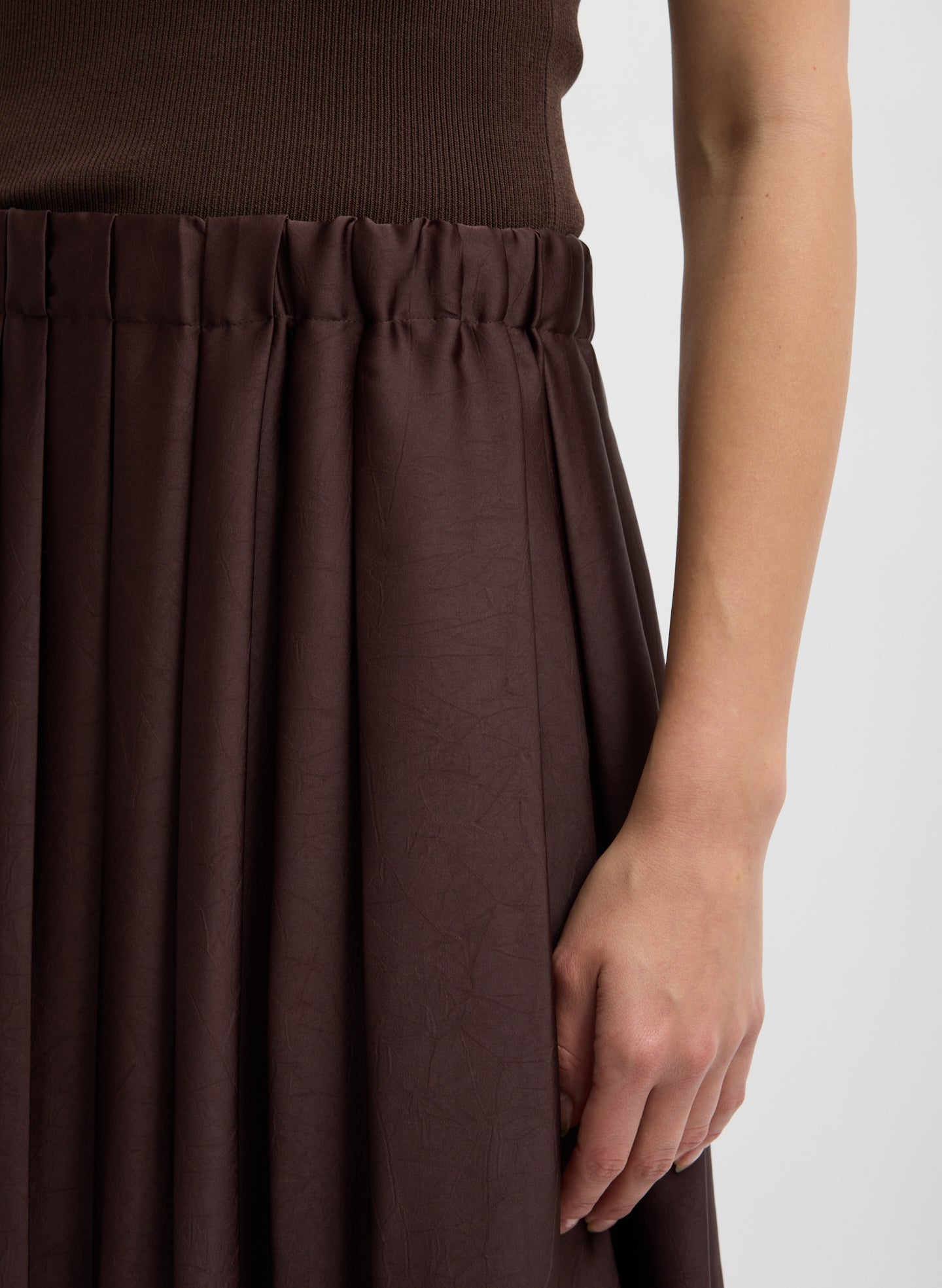 Brown skirt worn by a person on a white background highlighting the waistband