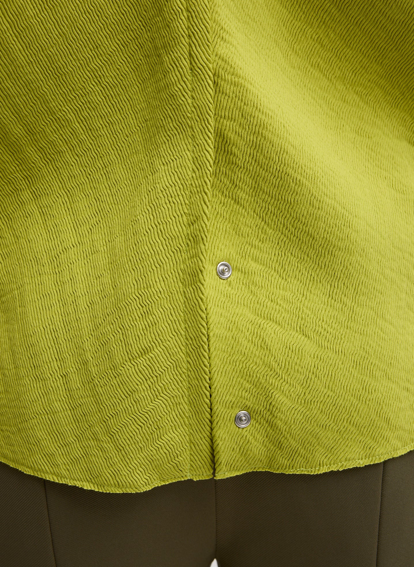 Chartreuse Viscose Plisse Hinged Long Sleeve Top - closeup of snap details at hem