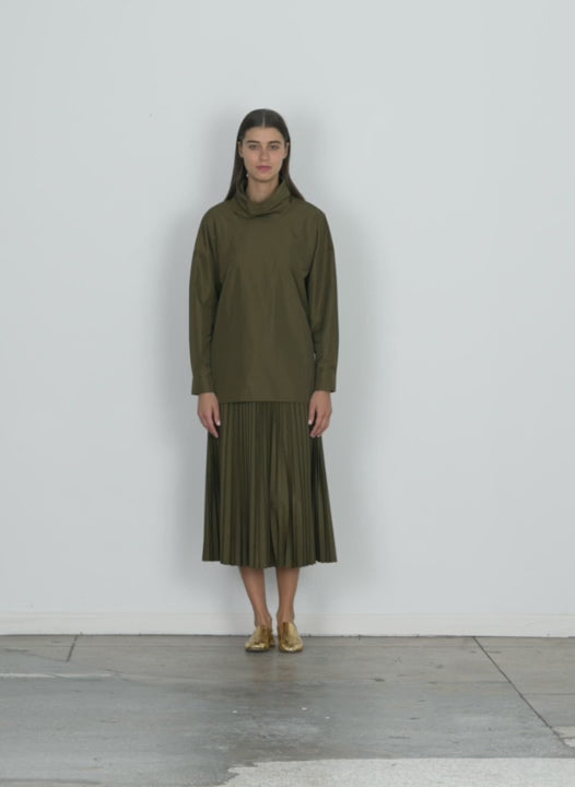 Model wearing the italian sporty nylon sunray pleated pull on skirt wood walking forward and turning around