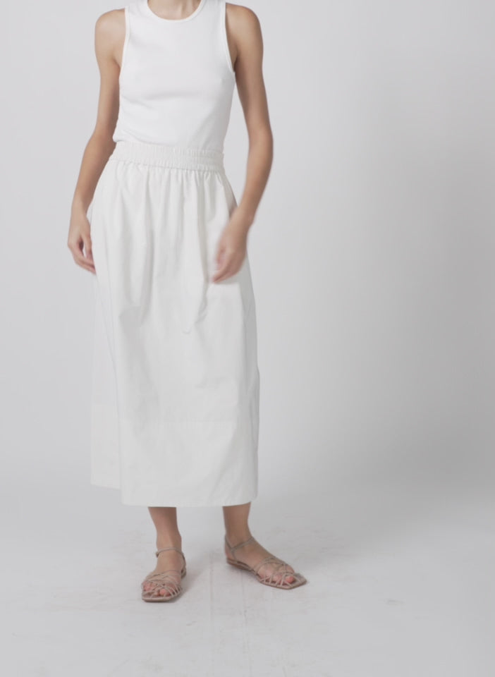 Model wearing the nylon pull on full skirt white walking forward and turning around