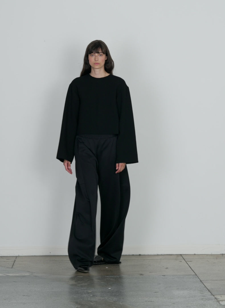 Model wearing the active knit winslow pant petite black walking forward and turning around