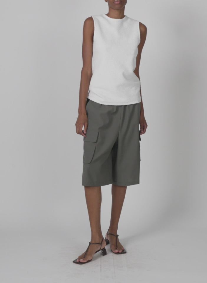 Model wearing the tropical wool relaxed cargo short dark stone walking forward and turning around