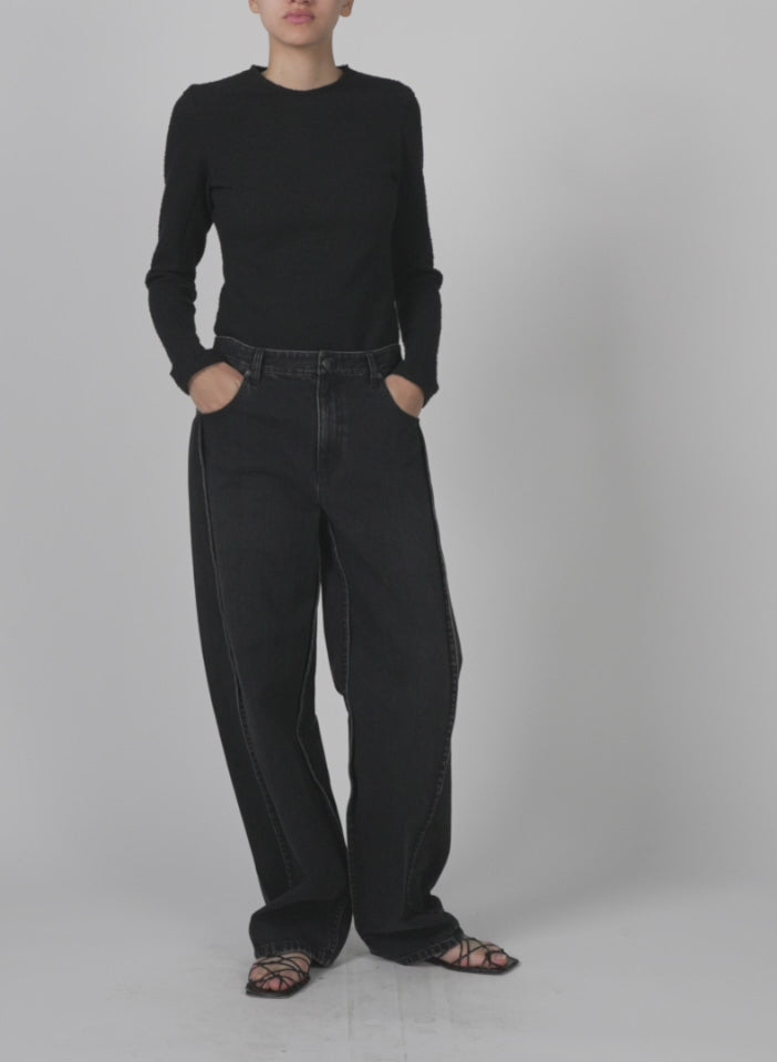 Model wearing the vintage black denim tuck jean vintage black walking forward and turning around