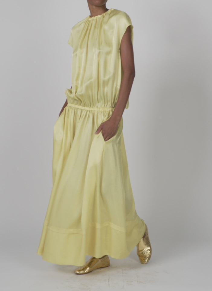 Model wearing the spring acetate shirred circular dress yellow walking forward and turning around