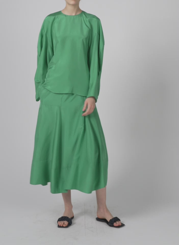 Model wearing the silk habutai circular top green tea walking forward and turning around