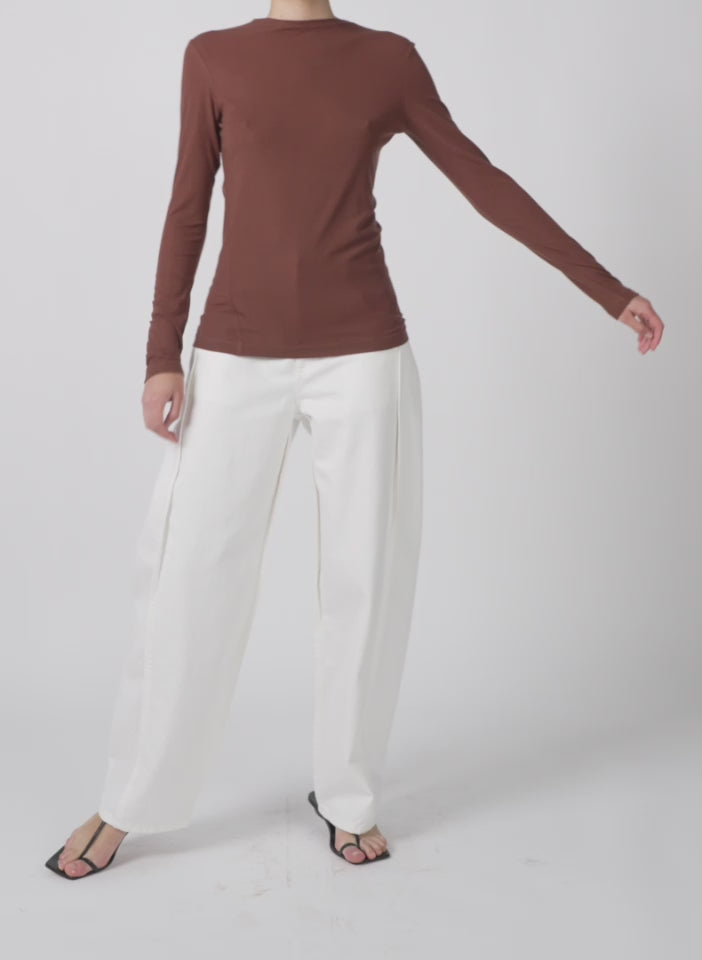 Model wearing the tencel knit twisted seam long sleeve t brown walking forward and turning around