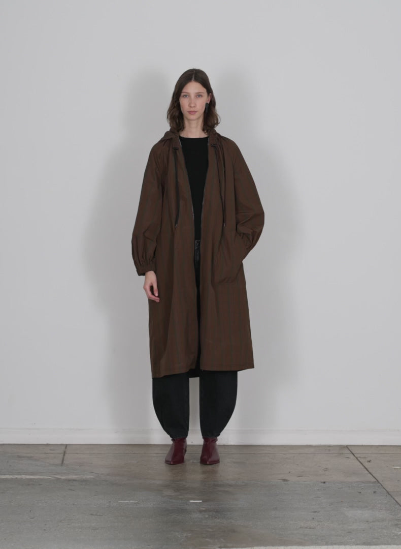 Model wearing the plaid tech poly long anorak brown multi walking forward and turning around