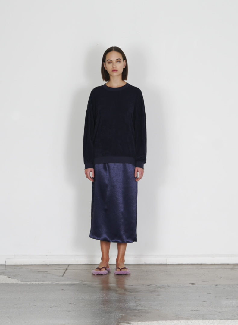 Model wearing the summer satin slip skirt dark navy walking forward and turning around