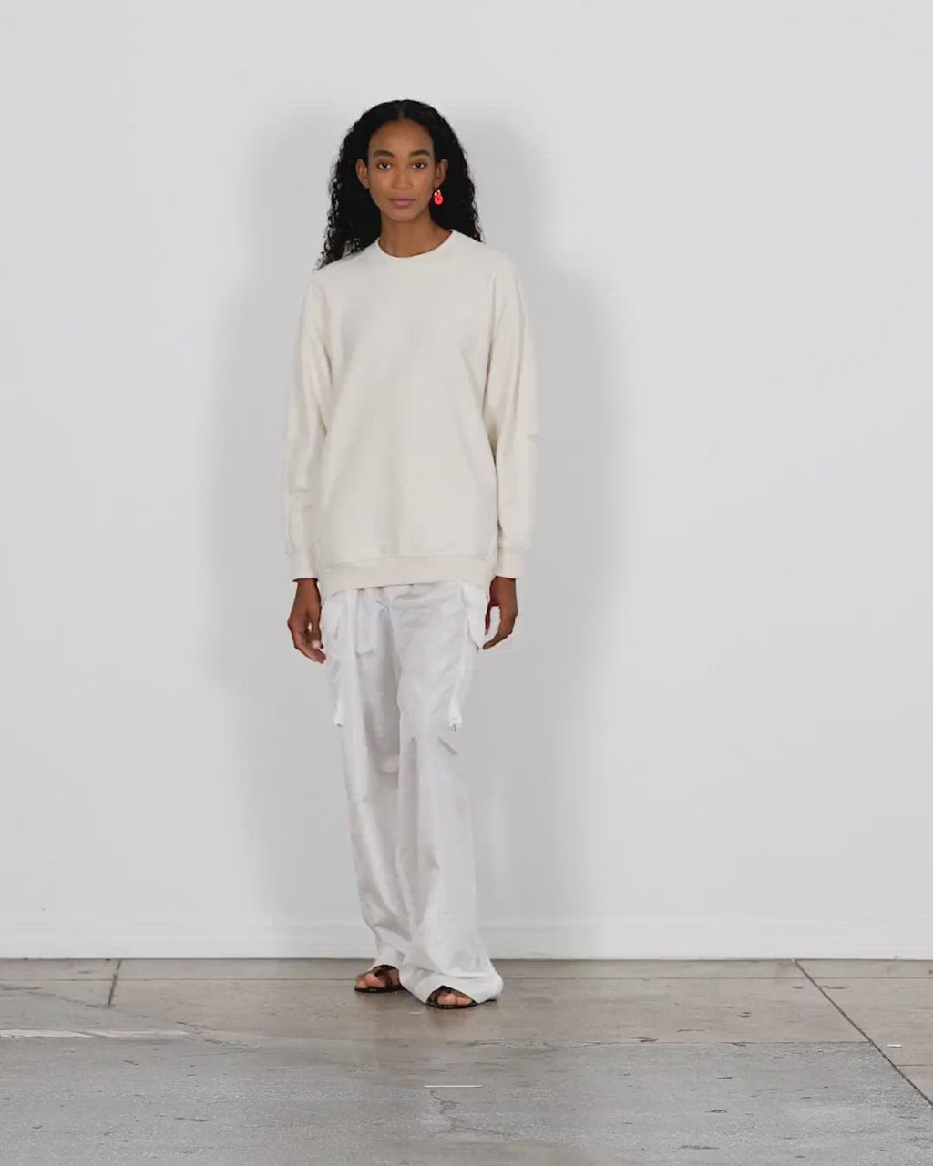 Model wearing the cocoon crewneck sweatshirt ivory walking forward and turning around