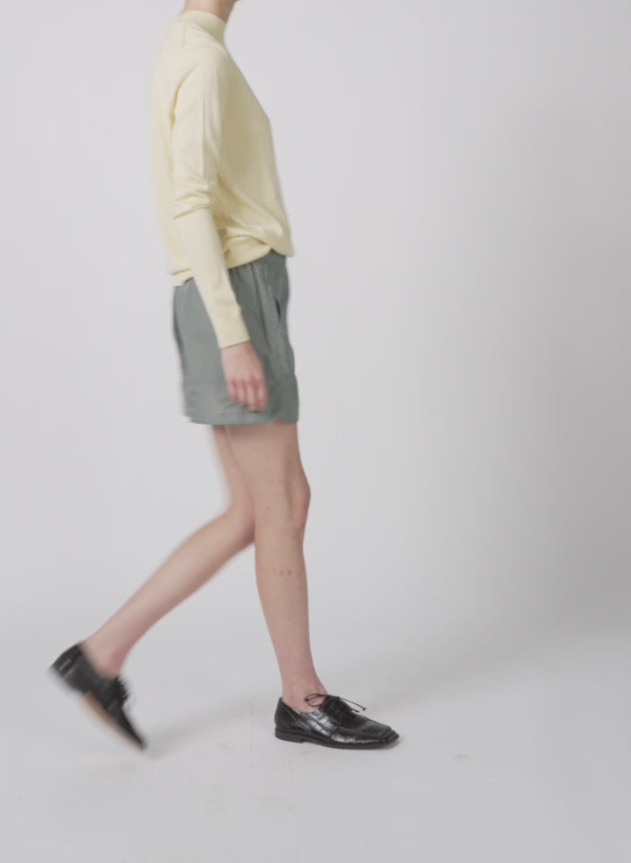 Model wearing the cashmere silk blend mock neck easy sweater lemon ice walking forward and turning around