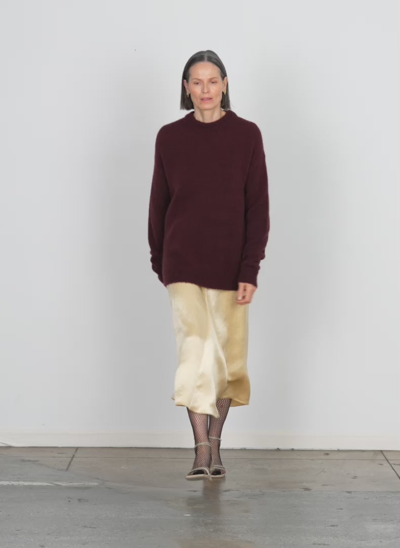 Model wearing the soft mohair crewneck easy pullover with slit cuffs garnet walking forward and turning around