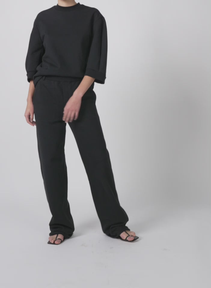 Model wearing the short sculpted sleeve sweatshirt black walking forward and turning around