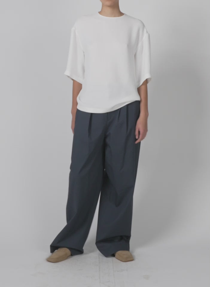 Model wearing the oliver cotton stretch tricotine stella pant slate blue walking forward and turning around