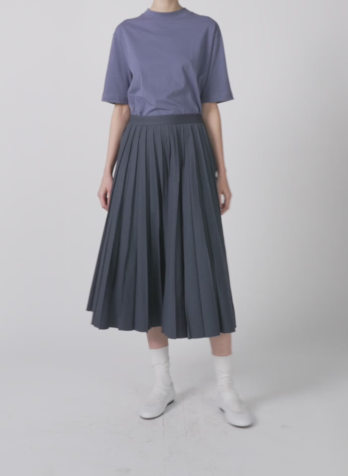 Model wearing the oliver cotton stretch tricotine pintucked skirt slate blue walking forward and turning around