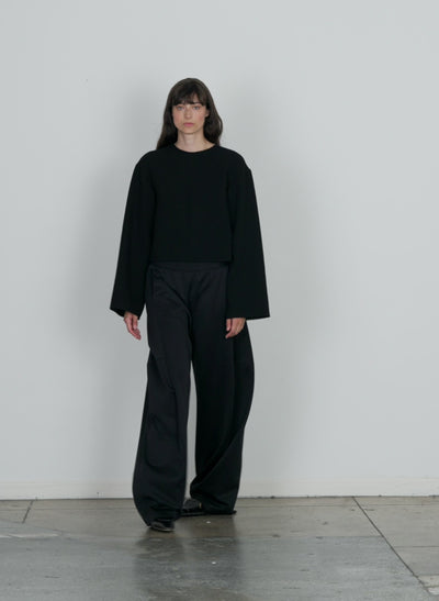 Model wearing the melee crepe long sleeve cropped top black walking forward and turning around