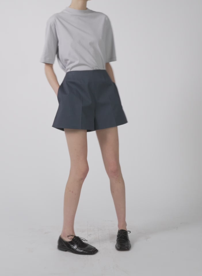 Model wearing the oliver cotton stretch tricotine structured shorts slate blue walking forward and turning around