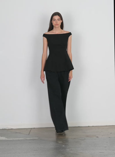 Model wearing the black denim stella petite length pant black walking forward and turning around