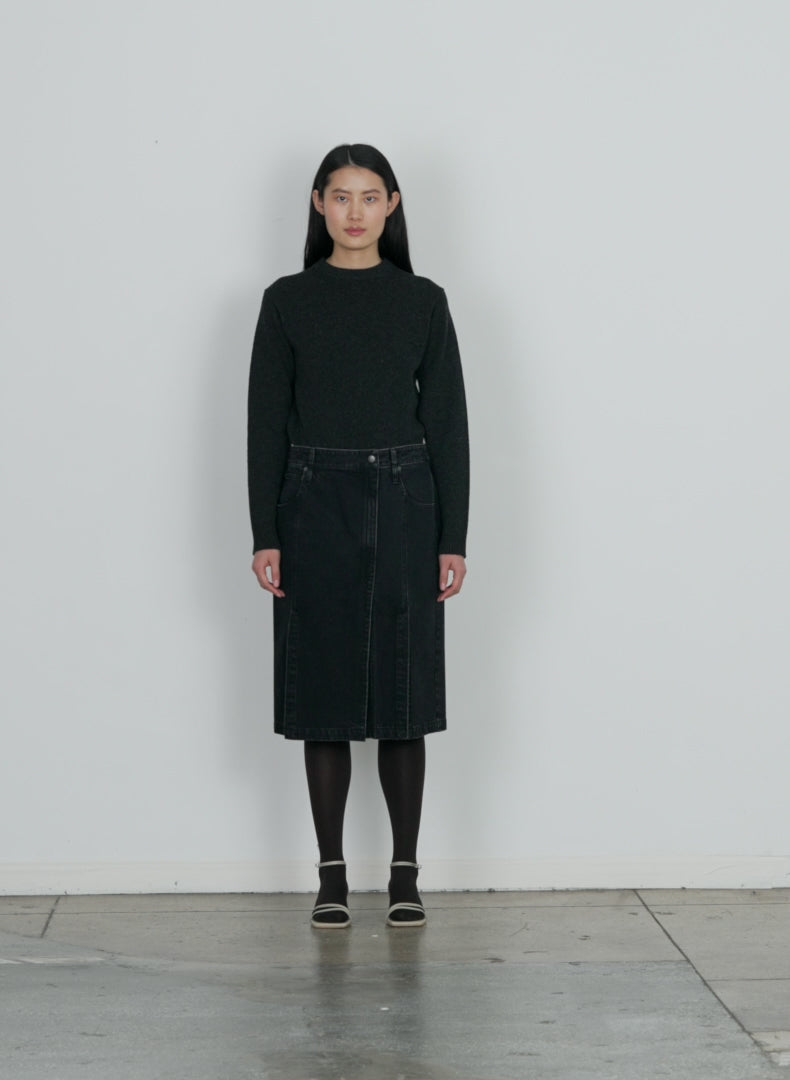 Model wearing the black denim paneled skirt black walking forward and turning around