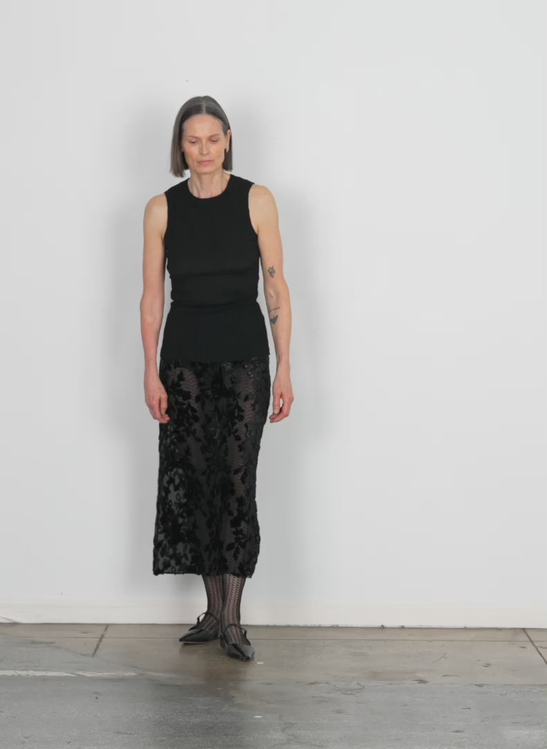 Model wearing the ione velvet burnout slip skirt black walking forward and turning around