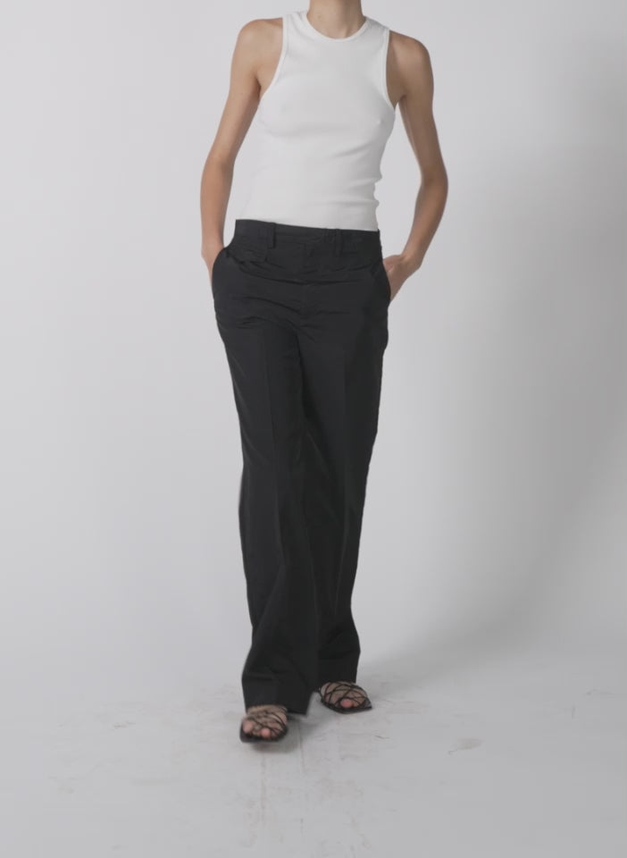 Model wearing the silk nylon straight leg trouser black walking forward and turning around