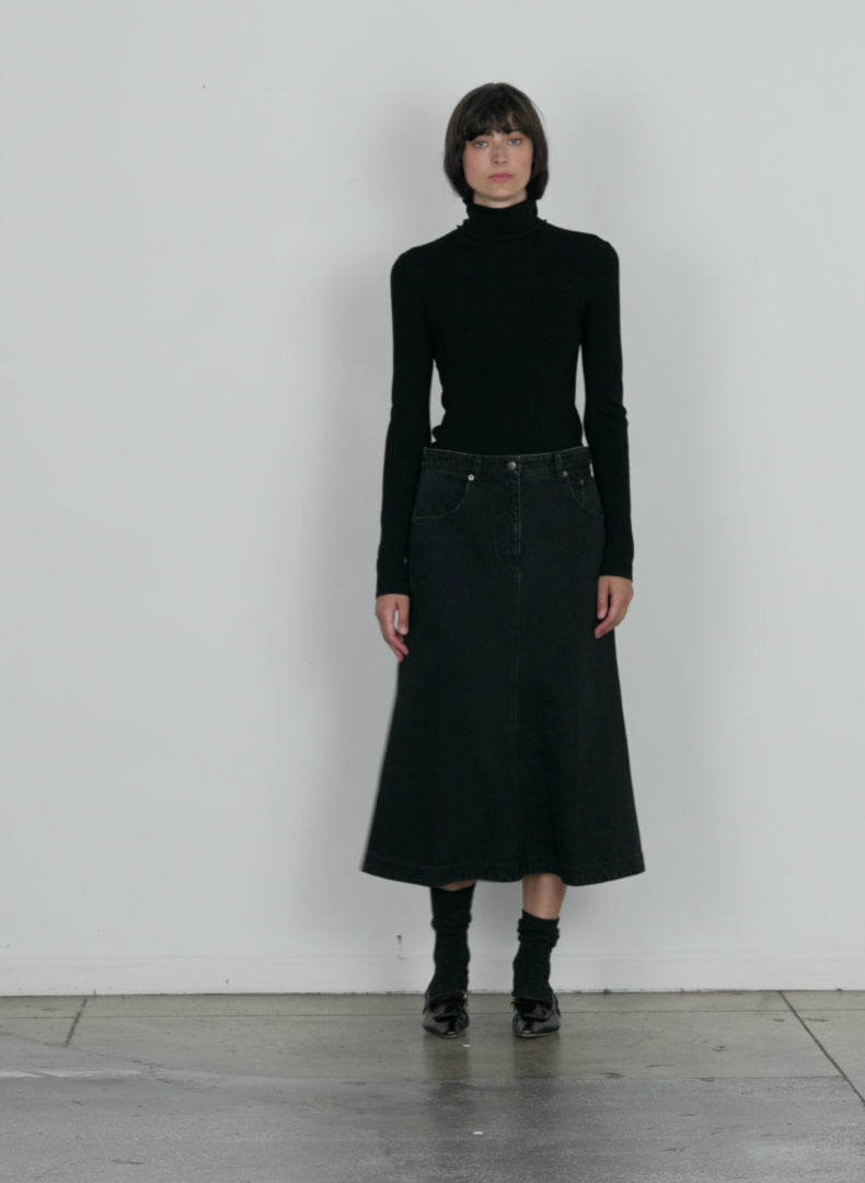 Model wearing the black denim midi aline skirt black walking forward and turning around