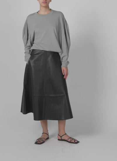 Model wearing the embossed python twill circle skirt black walking forward and turning around