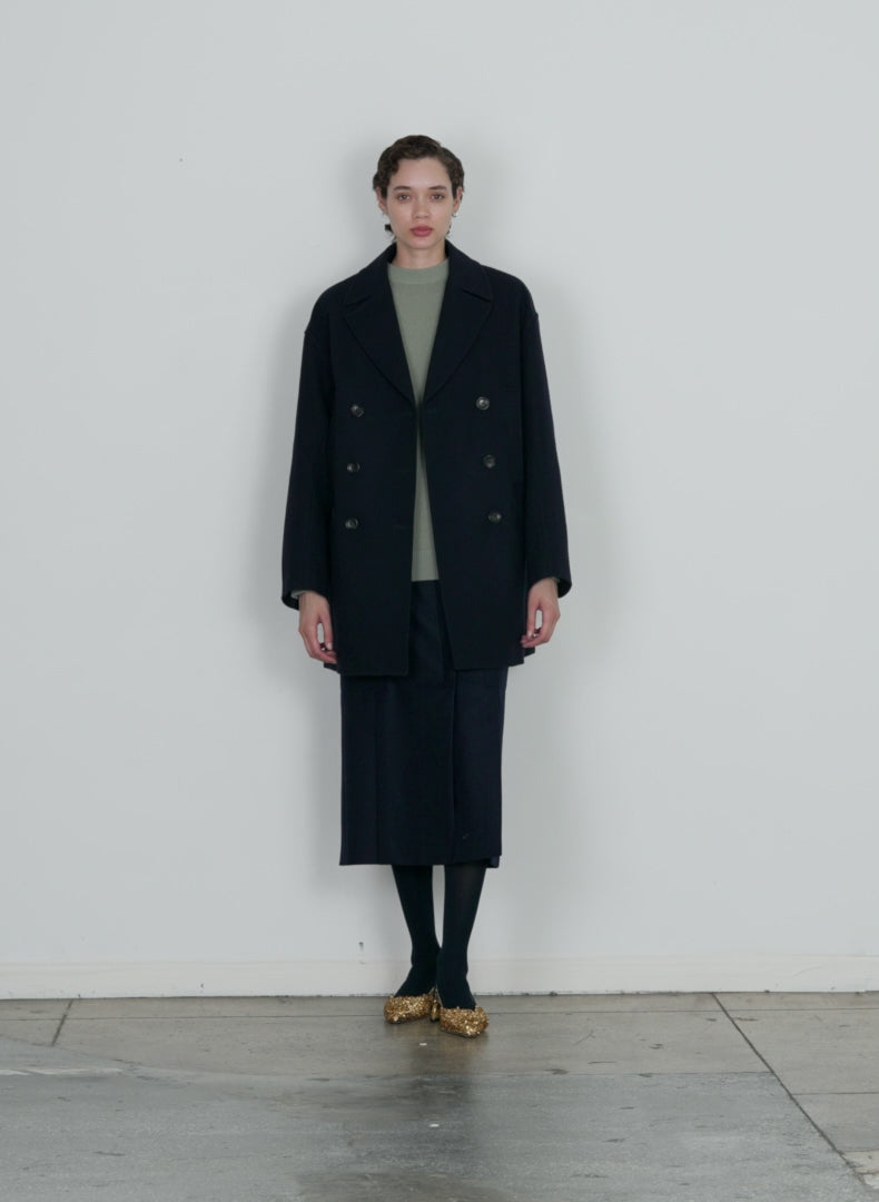 Model wearing the recycled felted wool peacoat navy walking forward and turning around