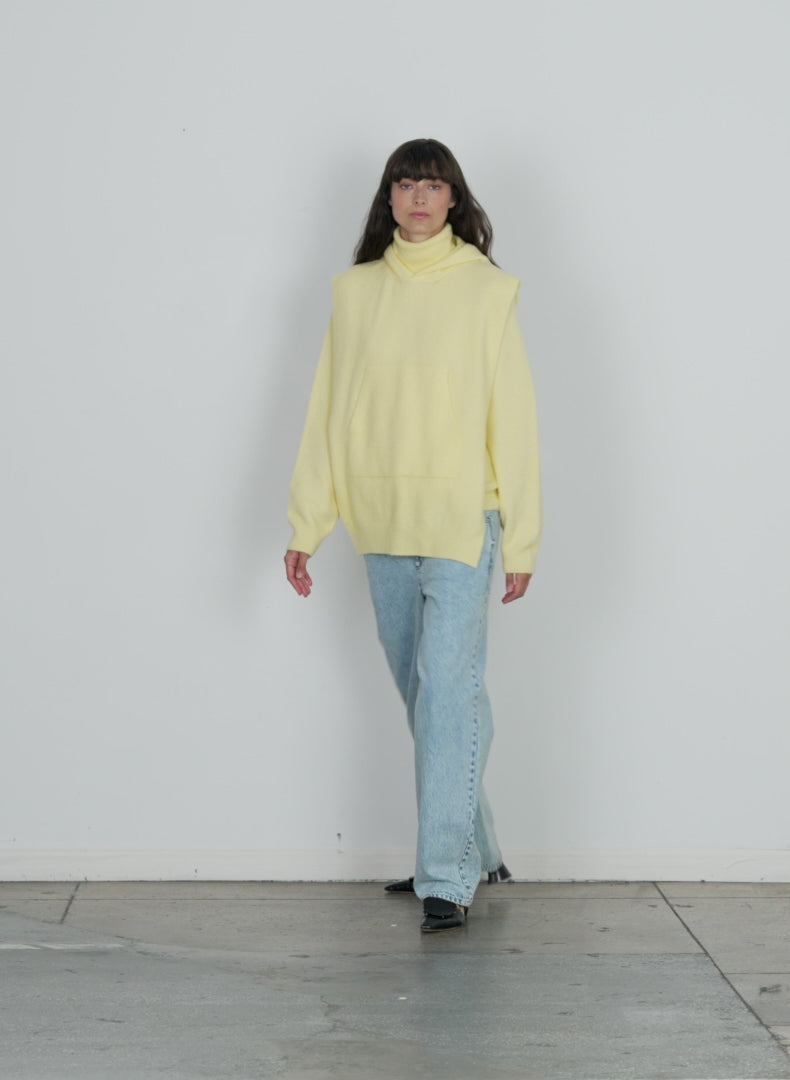 Model wearing the douillet hooded dickie yellow walking forward and turning around
