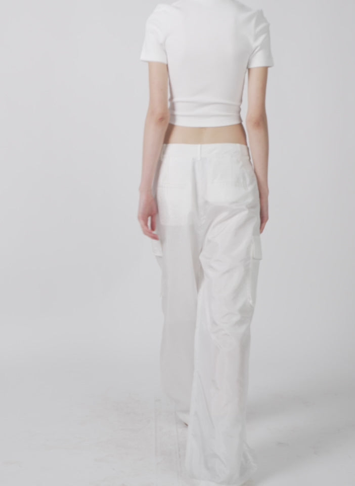 Model wearing the stella crispy nylon pleated cargo pant white walking forward and turning around