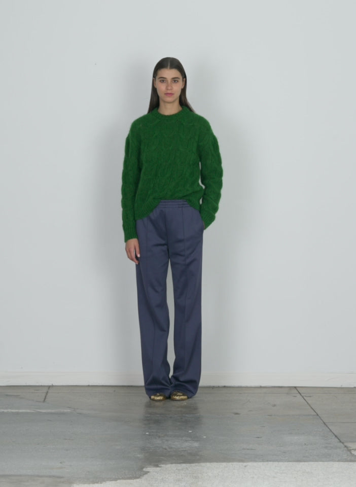 Model wearing the soft mohair cable crewneck easy pullover grass walking forward and turning around