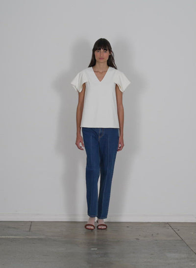 Model wearing the chalky drape vneck top with folded sleeve white walking forward and turning around