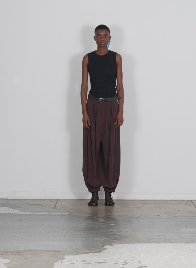 Model wearing the eco silk long eden pleated balloon pant brown walking forward and turning around
