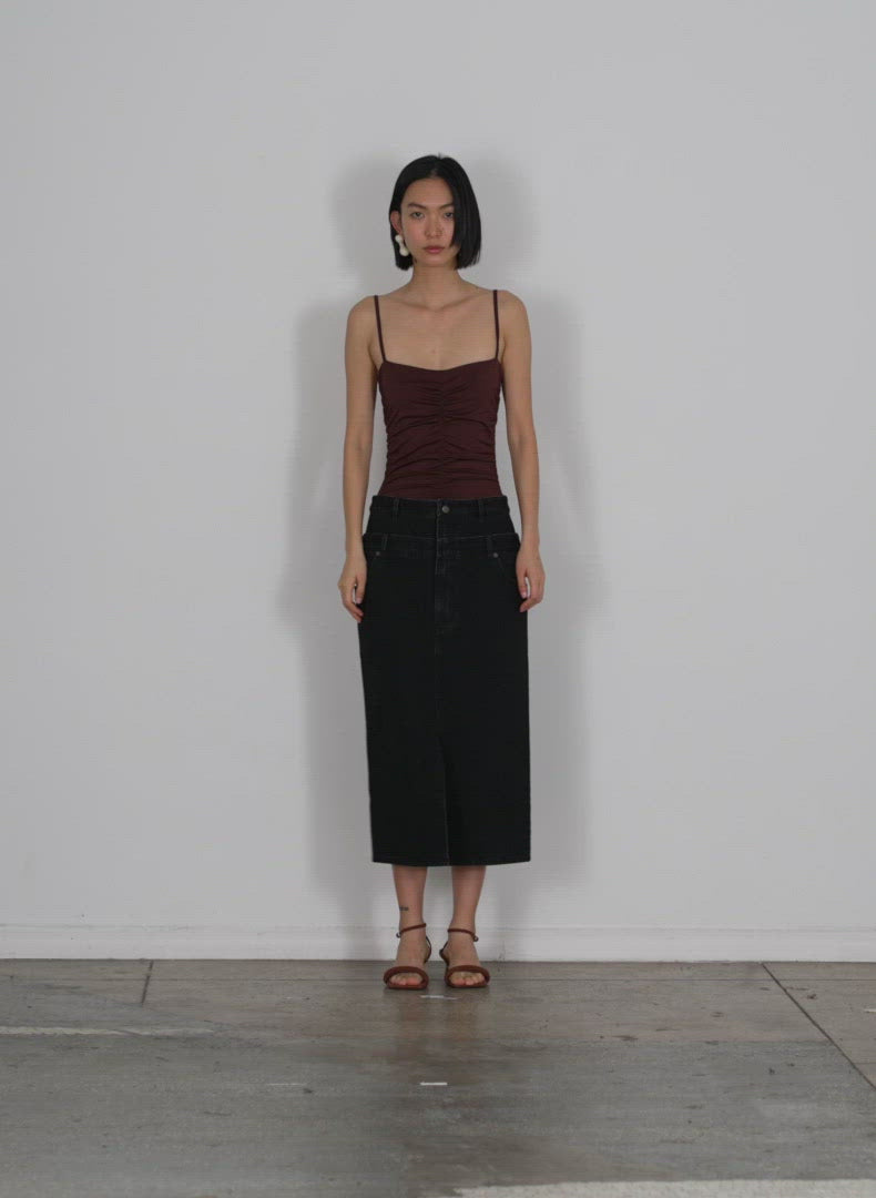 Model wearing the double waisted black denim skirt black walking forward and turning around