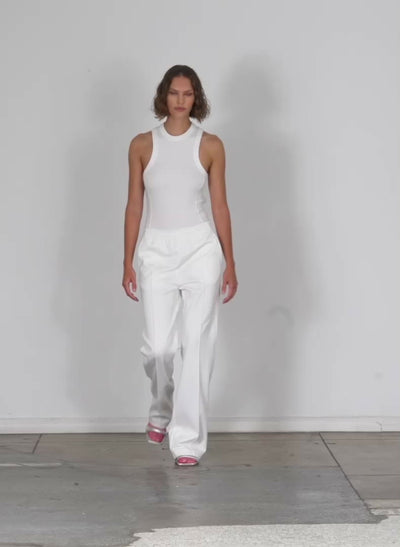 Model wearing the ribbed t racerback bodysuit white walking forward and turning around