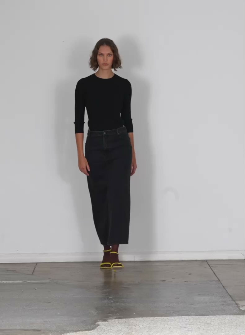 Model wearing the black denim maxi skirt black walking forward and turning around