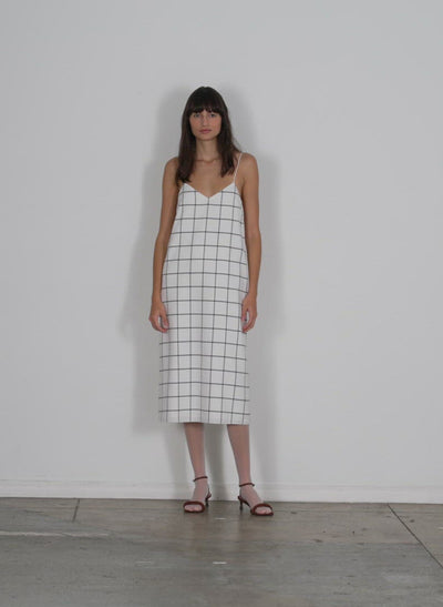 Model wearing the windowpane techy twill slip dress white black multi walking forward and turning around