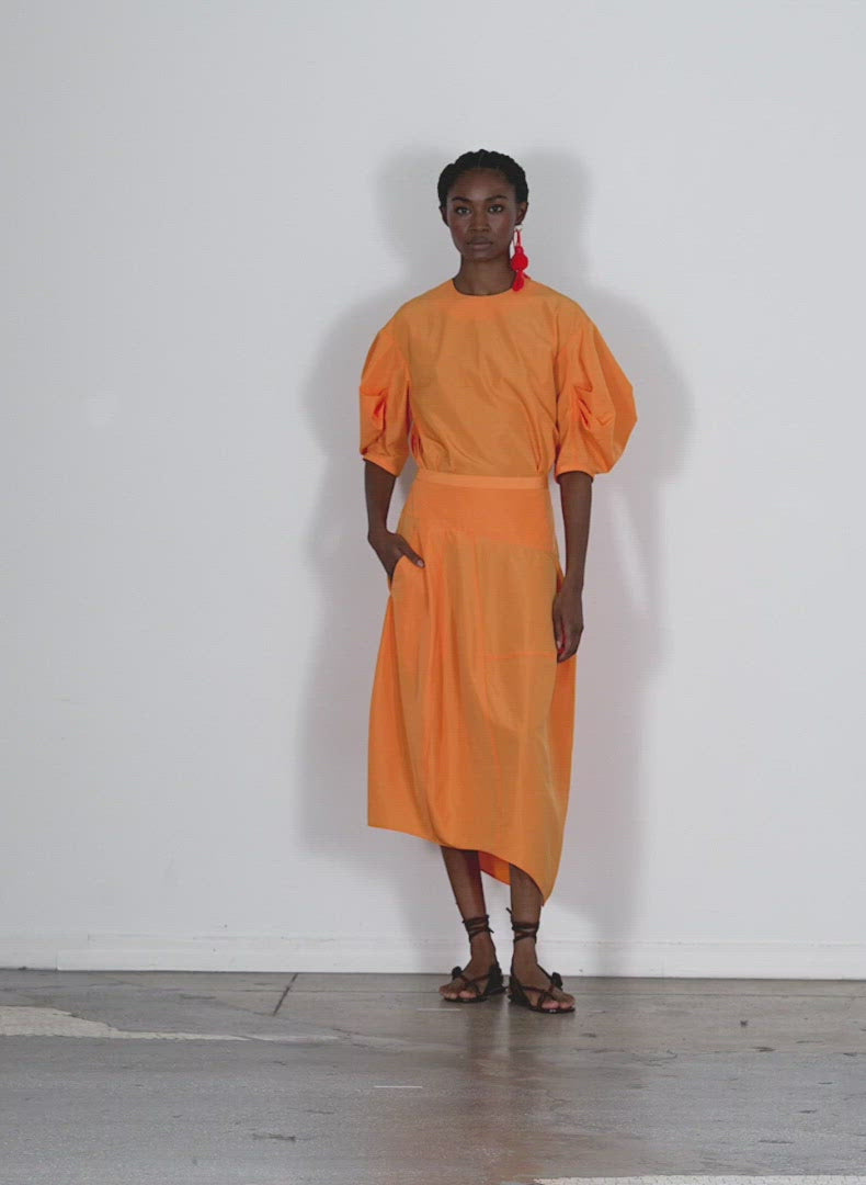 Model wearing the italian sporty nylon petite asymmetrical balloon s orange walking forward and turning around