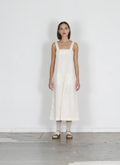 Model wearing the eco poplin overall midi dress cream walking forward and turning around