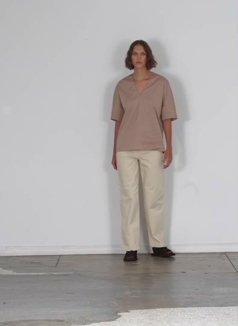 Model wearing the eco poplin vneck cocoon top sand walking forward and turning around