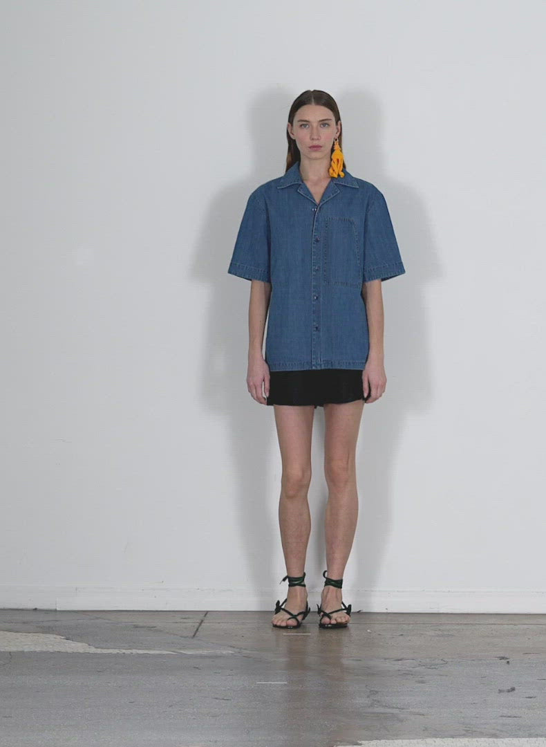 Model wearing the summer denim camp shirt light denim walking forward and turning around