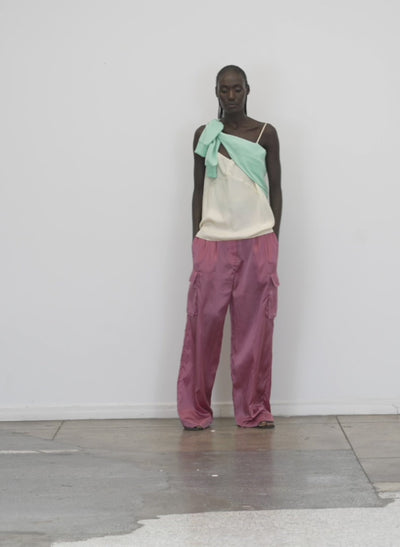 Model wearing the shiny nylon pleated stella cargo pant rose walking forward and turning around