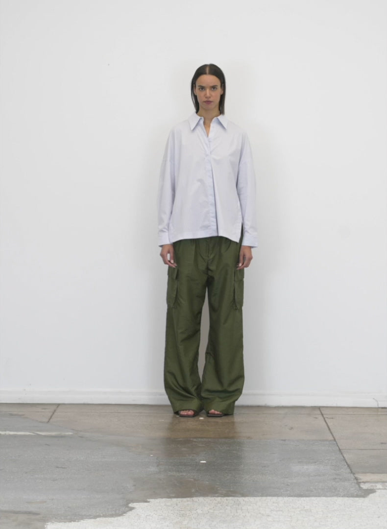 Model wearing the crispy nylon pleated cargo pant army green walking forward and turning around