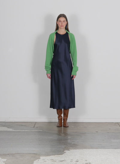 Model wearing the airy extrafine wool sleeve shrug powdery green walking forward and turning around