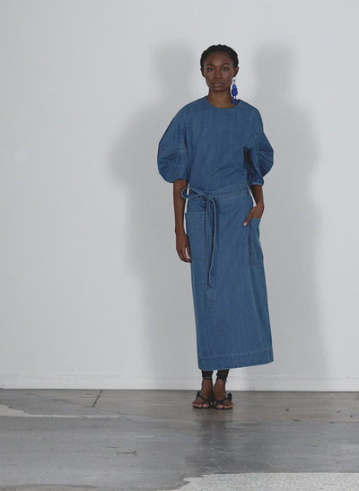 Model wearing the summer denim lean back wrap skirt light denim walking forward and turning around