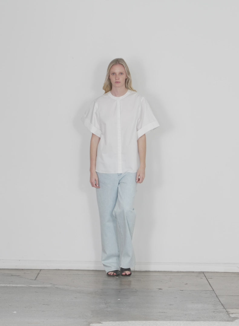 Model wearing the eco poplin new rolled sleeve shirt white walking forward and turning around