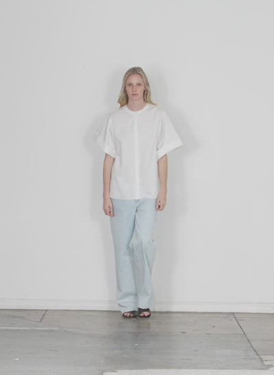 Model wearing the eco poplin new rolled sleeve shirt white walking forward and turning around