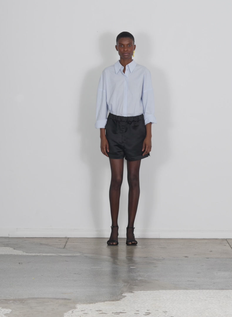 Model wearing the satin pull on shorts black walking forward and turning around