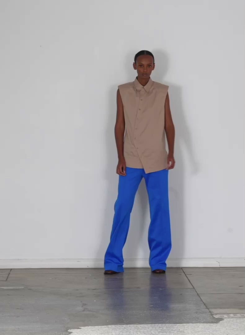 Model wearing the eco poplin sleeveless shoulderpad shirt sand walking forward and turning around