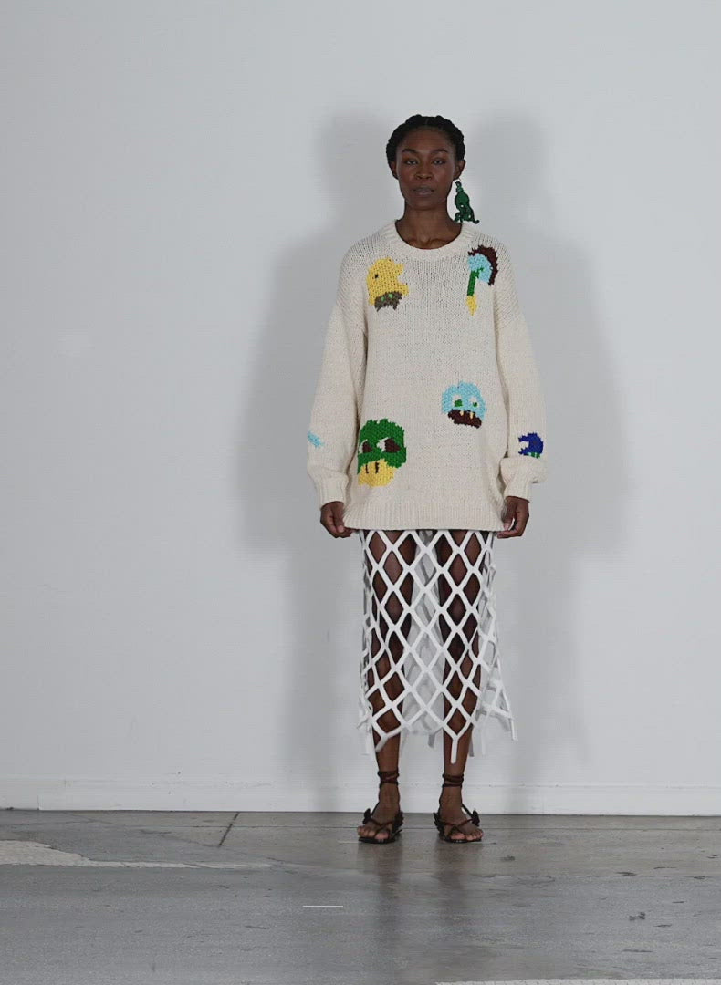 Model wearing the handknit intarsia crewneck pullover pop multi walking forward and turning around